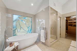 Full bath with radiator, a shower stall, lofted ceiling, a freestanding bath, and speckle patterned floor