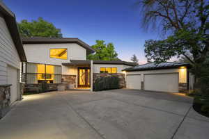 Modern home with stone siding, a standing seam roof, a 4 garage, and metal roof