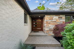 View of exterior entry featuring brick and stone work