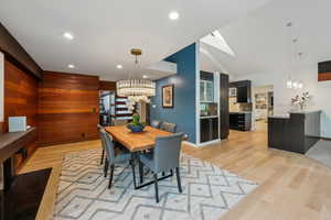 Dining space with a chandelier, light wood-style floors, recessed lighting, a skylight, and vaulted ceiling