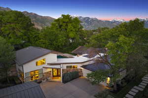Back of house at dusk with a mountain view, stone siding, a garage, and concrete driveway