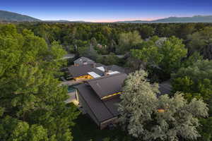 Aerial view of property and surrounding area featuring a heavily wooded area and a mountainous background