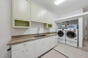 Washroom with independent washer and dryer and light tile patterned flooring