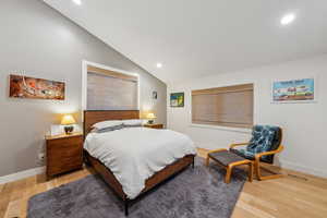 Bedroom with vaulted ceiling, light wood-style flooring, recessed lighting, and baseboards