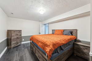 Bedroom featuring dark wood-type flooring, a textured ceiling, and baseboards
