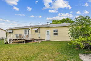 Rear view of house featuring a wooden deck and a yard