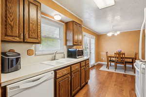 Kitchen with a sink, stainless steel microwave, dishwasher, range with electric cooktop, and light wood finished floors