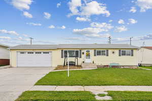Single story home with a garage, driveway, and a front lawn