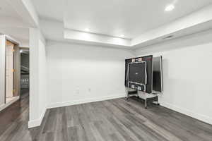 Unfurnished living room with wood finished floors, baseboards, recessed lighting, and a raised ceiling