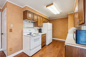 Kitchen with white appliances, brown cabinets, wood-type flooring, a textured ceiling, and light countertops