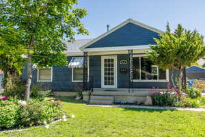 Bungalow-style house featuring covered porch, a front yard, and a shingled roof