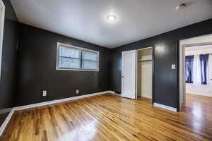 Unfurnished bedroom with light wood-style floors, baseboards, and a closet