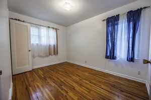 Empty room with hardwood / wood-style flooring and baseboards