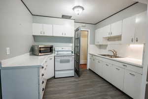 Kitchen featuring stainless steel microwave, white electric stove, a sink, and light countertops