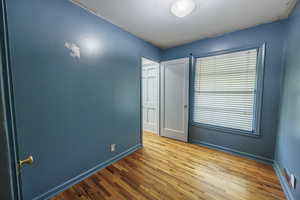 Unfurnished bedroom with wood finished floors and baseboards