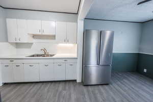 Kitchen with freestanding refrigerator, a sink, light wood-type flooring, and light countertops