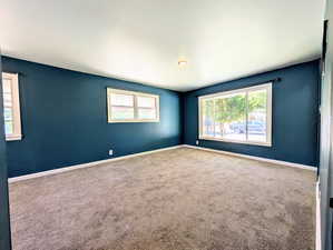 Carpeted spare room featuring baseboards