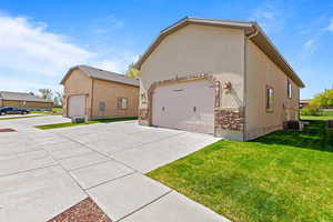 View of side of home featuring concrete driveway, a lawn, and stucco siding