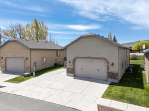 View of front of property with a garage, a front lawn, concrete driveway, stucco siding, and stone siding
