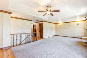 Empty room with ceiling fan, a raised ceiling, a smoke detector, carpet flooring, and ornamental molding