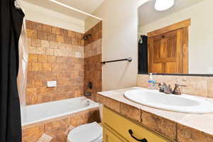 Full bath with vanity, tiled shower / bath, and toilet
