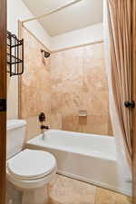 Full bathroom with shower / bath combo, toilet, and tile patterned flooring