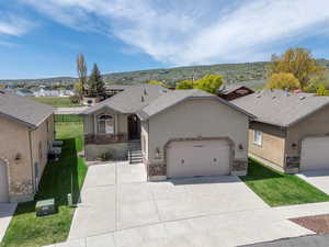 Single story home featuring stucco siding, a garage, stone siding, and a front lawn