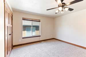 Empty room featuring carpet floors, baseboards, and ceiling fan