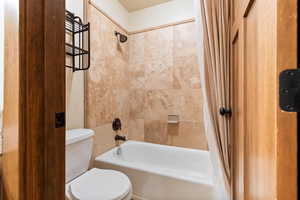 Full bathroom with shower / bath combination with curtain and toilet