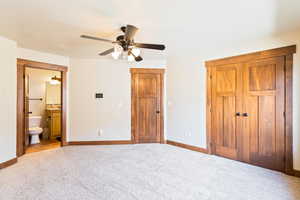 Unfurnished bedroom featuring light carpet, baseboards, ensuite bathroom, and ceiling fan