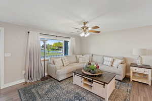 Living area with a ceiling fan, wood finished floors, and baseboards