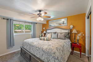 Carpeted bedroom with baseboards, a textured ceiling, and a ceiling fan