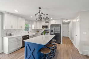 Kitchen featuring appliances with stainless steel finishes, a sink, light wood-type flooring, decorative backsplash, and recessed lighting