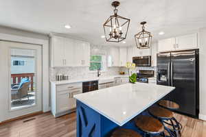 Kitchen with appliances with stainless steel finishes, a sink, white cabinetry, backsplash, and recessed lighting