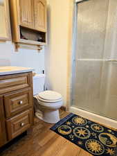Bathroom featuring vanity, a shower stall, toilet, and wood finished floors