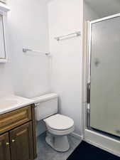 Bathroom featuring vanity, a stall shower, toilet, and baseboards