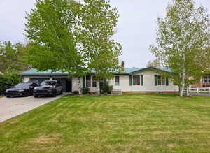 Single story home with driveway, a garage, a chimney, and metal roof