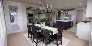 Dining room with light wood finished floors, a fireplace, and recessed lighting