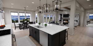 Kitchen featuring dark cabinets, a chandelier, a mountain view, light wood finished floors, and light stone counters