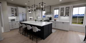 Kitchen featuring glass insert cabinets, wall chimney range hood, pendant lighting, a kitchen island with sink, and recessed lighting