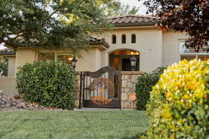 View of front of property with a gate, stucco siding, a tiled roof, and a front yard