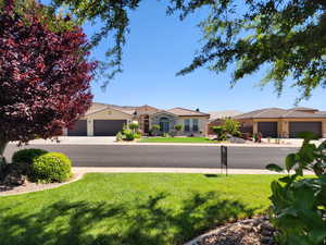 View of front of property with a front lawn, stucco siding, stone siding, and a tiled roof