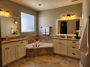 Full bathroom featuring two vanities and a garden tub