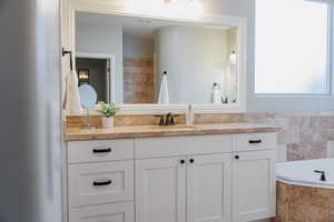 Bathroom with healthy amount of natural light, vanity, and a bath