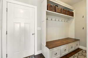 Mudroom featuring baseboards and dark wood-type flooring