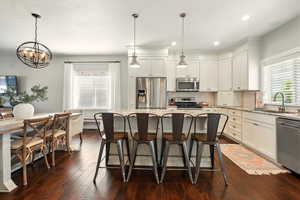 Kitchen with appliances with stainless steel finishes, a sink, a chandelier, light stone counters, and recessed lighting