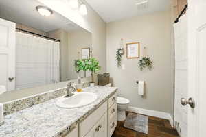 Full bathroom featuring wood finished floors, baseboards, vanity, and toilet