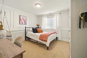 Bedroom featuring carpet flooring and a decorative wall