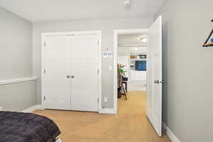 Bedroom with light carpet, baseboards, and a closet