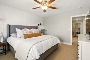 Bedroom with washer and dryer, light carpet, ceiling fan, and baseboards